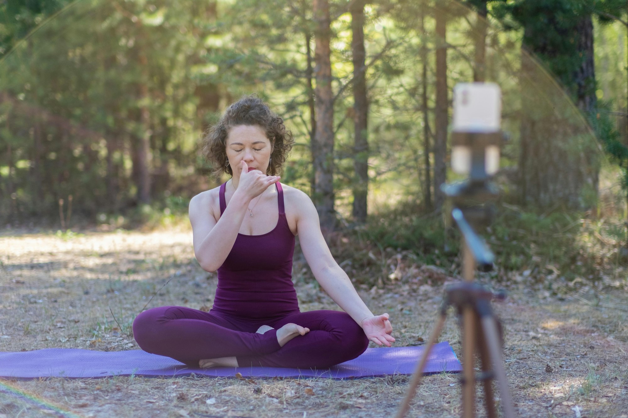 Breathing exercises of pranayama yoga of a young woman in nature in a forest park.