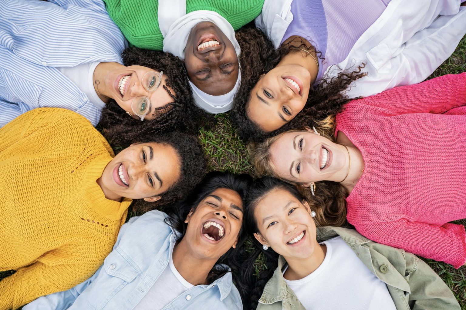 Multiracial group of young women in circle smiling at camera together